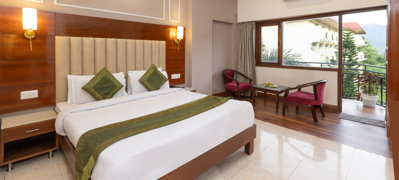 juSTa Riverside – Superior 2 King-size bed in a modern hotel room with green accents, wood headboard, and nightstands; seating area by a large window.