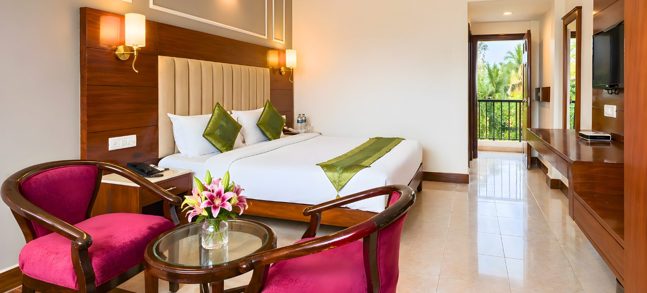 juSTa Riverside – Superior 4 Hotel room with a large bed, white linens, green pillows and runner, and a wooden headboard with twin wall lamps.