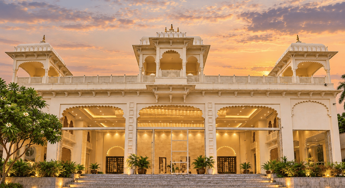 Monsoon 2 Luxurious white palace-style building with arches, warm interior lights, and tropical plants at dusk.
